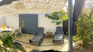 Un espace patio comprenant un barbecue, des sièges d’extérieur et une partie abritée avec un auvent décoratif.