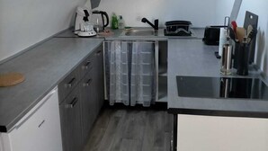 Eine kompakte Küche mit Einbauofen, Kaffeemaschine und Spüle.