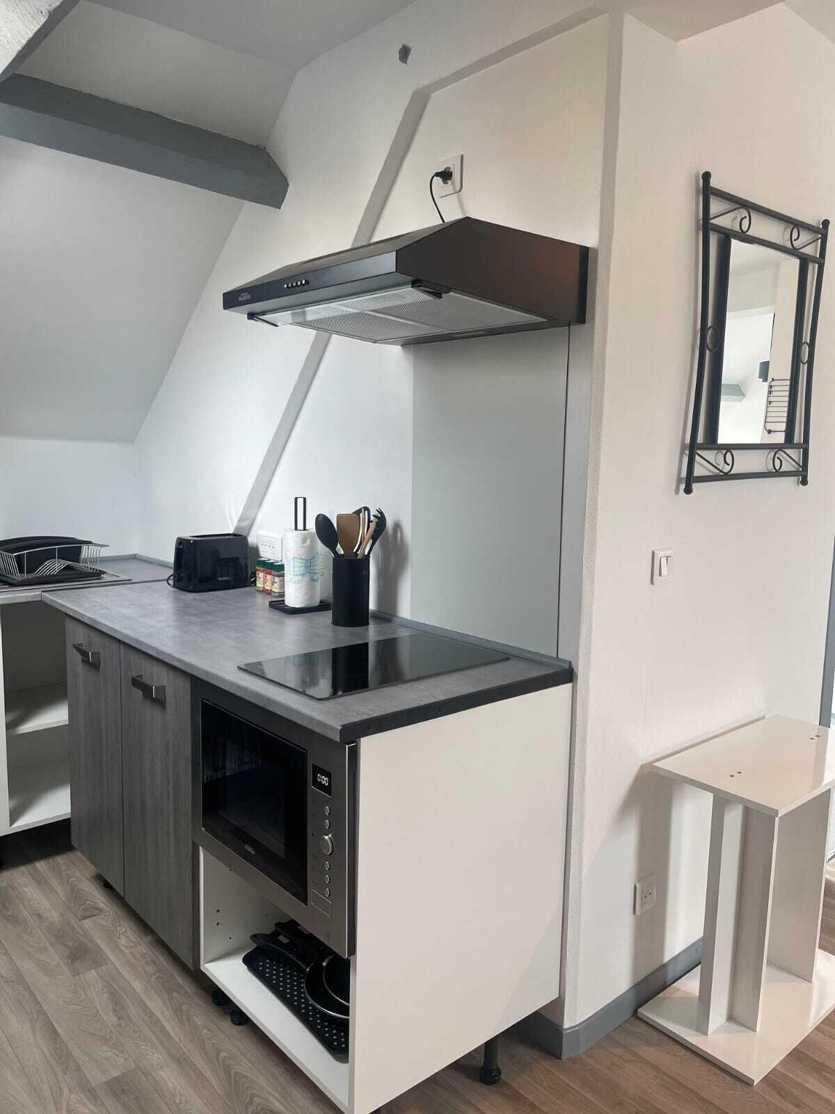 A modern kitchen with a built-in stove, a range hood, and a small countertop with kitchen utensils.
