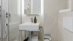 A modern bathroom with a glass shower enclosure, a white sink with a mirror above it, and a white bathtub. - 101 - Appart'Hôtel Neostelia-Annecy (Annecy)
