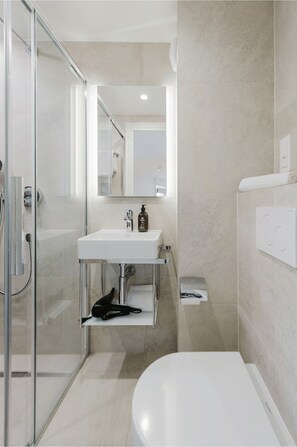 A modern bathroom with a glass shower enclosure, a white sink with a mirror above it, and a white bathtub. - 101 - Appart'Hôtel Neostelia-Annecy (Annecy)