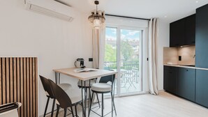 A modern kitchen with a dining area, large windows, and a view of the outdoors. - 101 - Appart'Hôtel Neostelia-Annecy (Annecy)