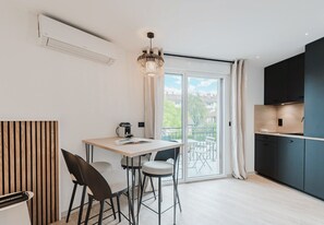 A modern kitchen with a dining area, large windows, and a view of the outdoors. - 101 - Appart'Hôtel Neostelia-Annecy (Annecy)