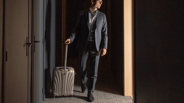 A man in a suit walking through a hotel corridor with a suitcase. - 101 - Appart'Hôtel Neostelia-Annecy (Annecy)