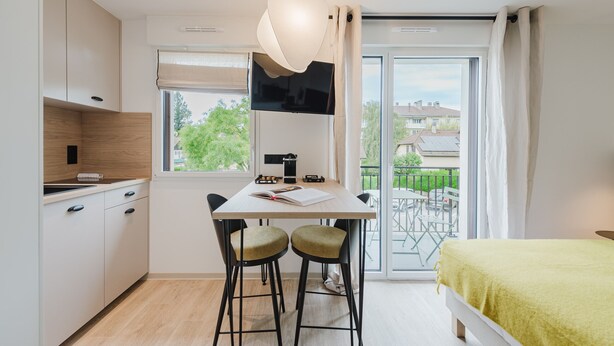 A modern kitchen with a dining area, a TV, and a balcony with a view. - 102 - Appart'Hôtel Neostelia-Annecy (Annecy)