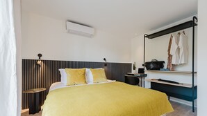 A modern bedroom with a bed, bedside table, and a mirror with clothes hanging. - 102 - Appart'Hôtel Neostelia-Annecy (Annecy)