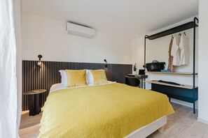 Ein modernes Schlafzimmer mit Bett, Nachttisch und Spiegel, an dem Kleidung hängt.