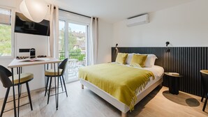 A modern bedroom with a bed, a desk with chairs, a TV, and a window with a view of the outside. - 102 - Appart'Hôtel Neostelia-Annecy (Annecy)