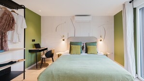 Ein modernes Schlafzimmer mit einem großen Bett, grünen Wänden, einem Schreibtisch und einem Sessel.