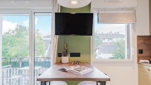 Eine moderne Küche mit großem Fenster, einem Flachbildfernseher und einer Essecke mit zwei Hockern.