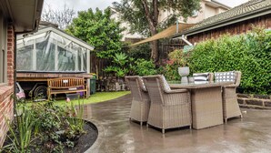 A patio with wicker furniture, a greenhouse, and a wooden fence. - Pet-friendly guesthouse with garden and playground (Ivanhoe)