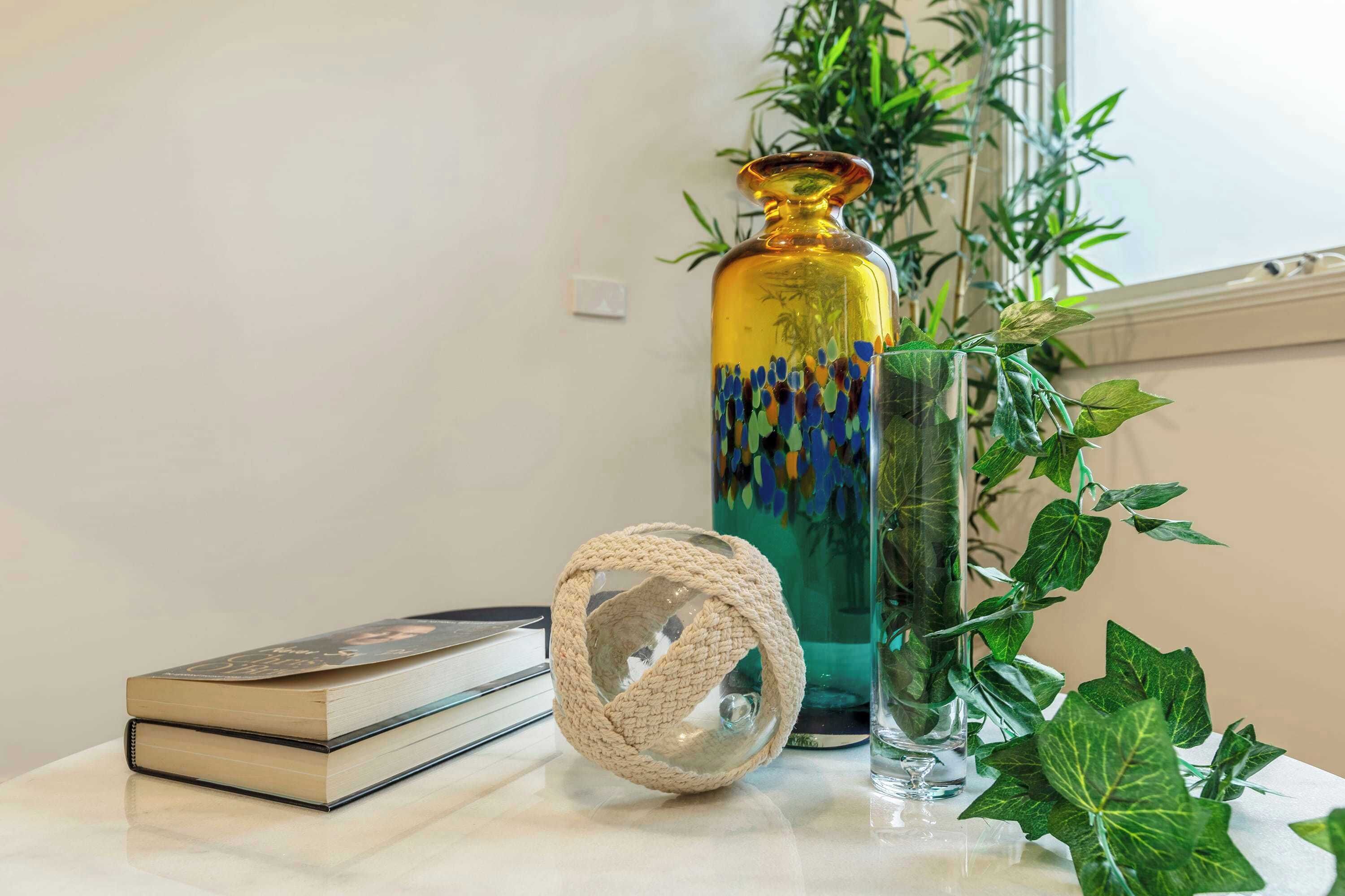 Une table sur laquelle se trouvent un vase en verre, un livre et un objet décoratif.