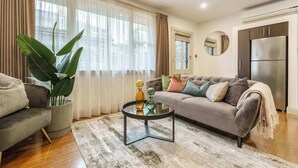 A living room with a sofa, coffee table, and a potted plant. - Pet-friendly guesthouse with garden and playground (Ivanhoe)