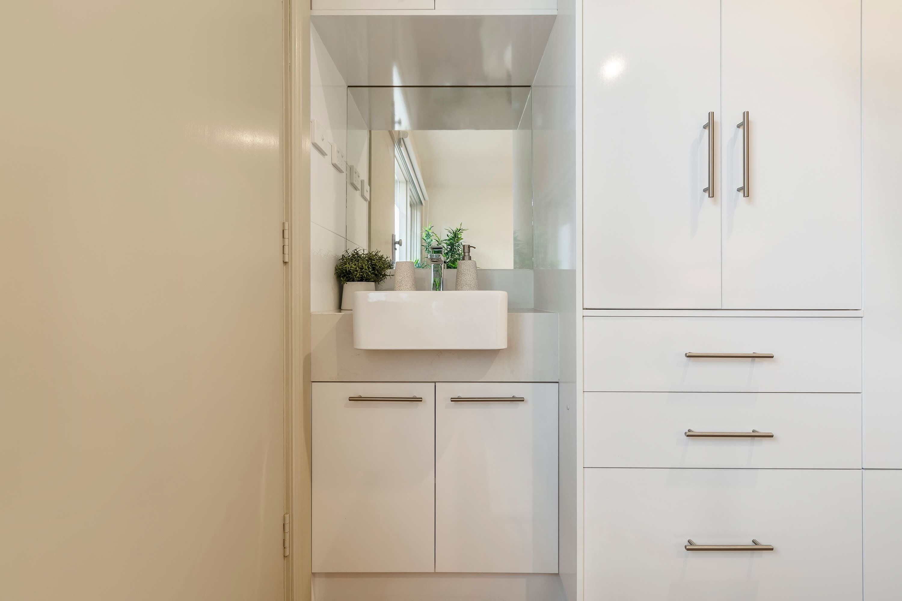 A modern bathroom with a white vanity, a mirror, and a sink.