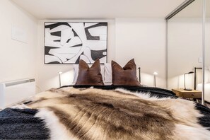 A bedroom with a large bed, a black and white abstract painting, a fur throw, and a bedside table with a lamp. - Hawthorn retreat with balcony near Swinburne uni (Hawthorn)