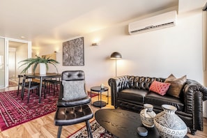 A living room with a leather sofa, a black armchair, a coffee table, and decorative vases. - Hawthorn retreat with balcony near Swinburne uni (Hawthorn)