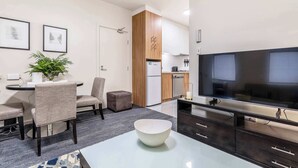 Ein modernes Wohnzimmer mit Essbereich, einer Küche und einem großen Flachbildfernseher.