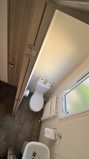 A compact bathroom with a toilet, a sink, and a window.