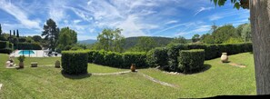 A well-maintained garden with a swimming pool, neatly trimmed hedges, and a clear view of the surrounding hills.