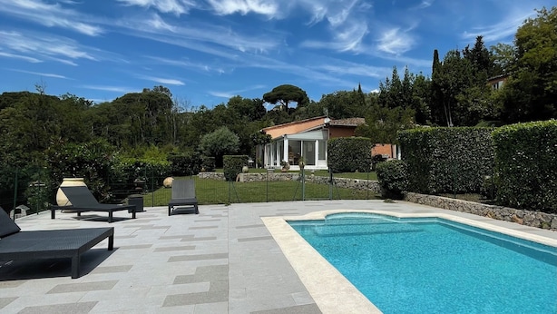 Ein Pool mit Liegestühlen und einer Terrasse mit Steinplatten.