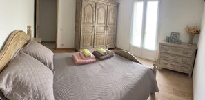 A bedroom with a bed, a wooden wardrobe, a dresser, and a window.