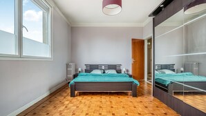 Un dormitorio con cama, ventana, radiador y espejo.