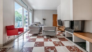 Una sala de estar moderna con piso a cuadros, una silla roja, un sofá gris y un televisor.