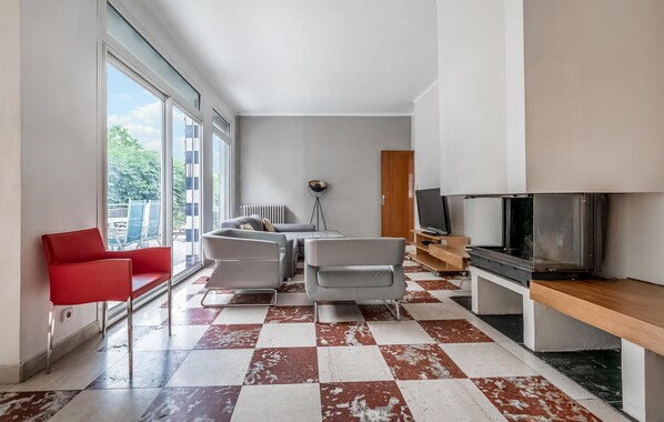 A modern living room with a checkered floor, a red chair, a grey sofa, and a television.