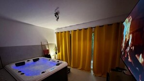 A room with a hot tub, yellow curtains, and a television. - Rheinmosel Glück Wellness (Koblenz)
