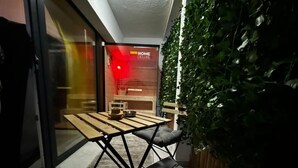A modern interior with a wooden table and black cushioned seating, a glass door with a red sign, and a green plant wall. - Rheinmosel Glück Wellness (Koblenz)