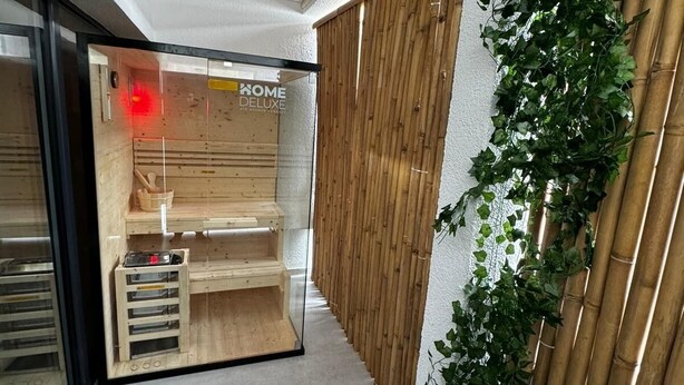 A modern interior with a wooden bench, a bamboo wall, and a glass door with a red light. - Rheinmosel Glück Wellness (Koblenz)