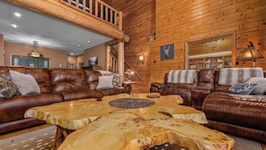 A cozy living room with two leather sofas, a coffee table with a natural wood top, and a wooden ceiling.
