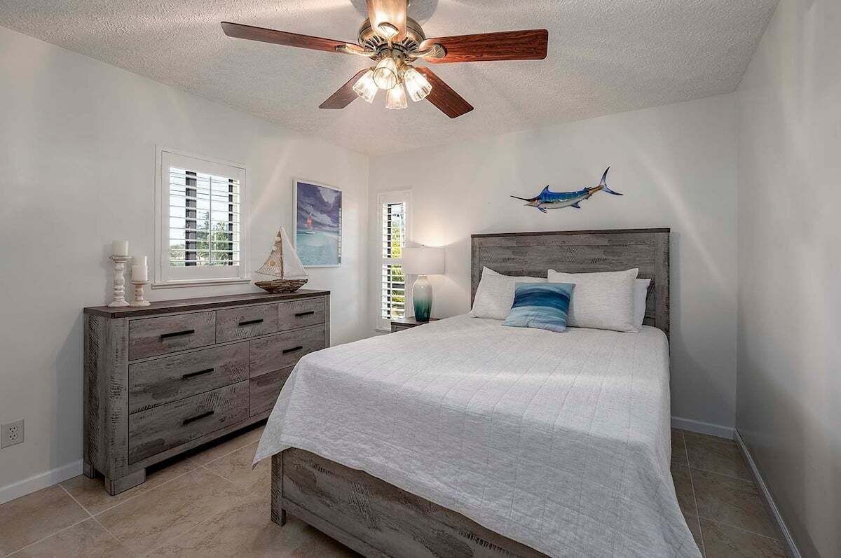 A bedroom with a bed, a dresser, a ceiling fan, and a wall-mounted airplane decoration.