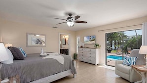 A bedroom with a bed, dresser, and a view of a swimming pool.