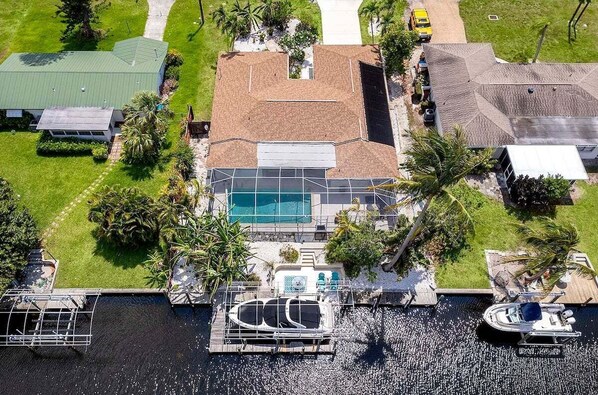 Eine Luftaufnahme eines Anwesens mit Swimmingpool, Bootssteg und Booten.