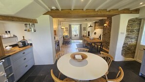 A modern kitchen with a round dining table, wooden chairs, and a stone accent wall.