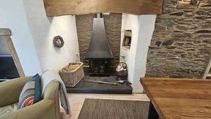 A cozy living room with a stone wall, a fireplace, a wicker basket, and a wooden table.