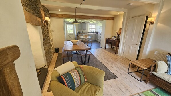 A cozy living area with a sofa, a dining table, and a kitchen in the background.