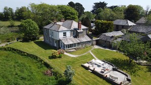 A large house with a spacious patio area, surrounded by lush greenery and other residential buildings.
