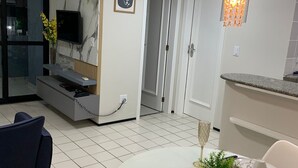 Ein moderner Essbereich mit einem runden Tisch für zwei Personen, einem an einer Marmorwand montierten Fernseher und einer Küchenzeile mit Arbeitsplatte.