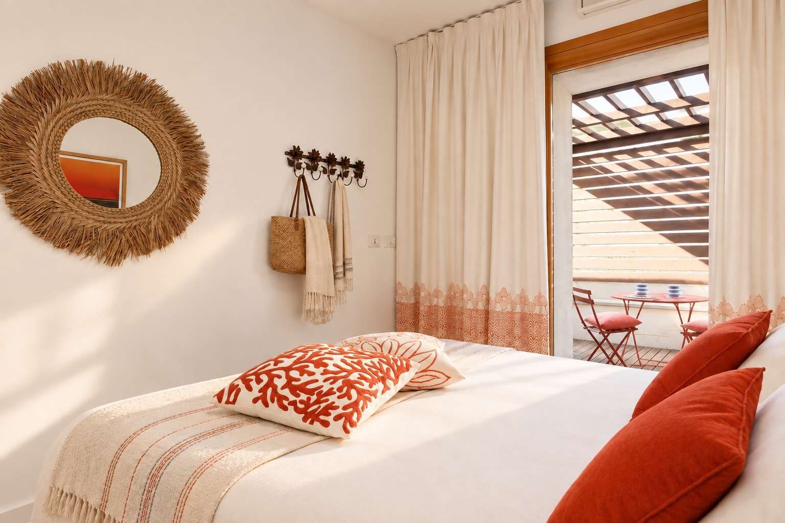 Una camera da letto con un letto, un cesto appeso, uno specchio e vista su uno spazio esterno con tavolo e sedie.