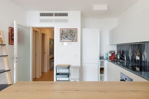 A modern kitchen with white cabinetry, a wooden countertop, and a view of the adjacent dining area.