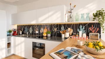 Eine moderne Küche mit weißen Schränken, einer schwarzen Spritzschutzwand und einer Holzausziehtafel.