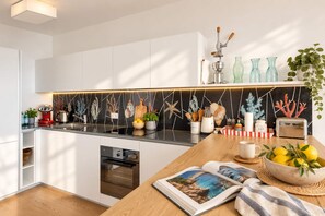A modern kitchen with white cabinets, a black backsplash, and a wooden countertop.