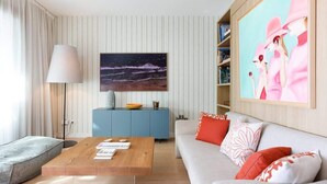 Een moderne woonkamer met een bank, een salontafel, een boekenkast en een schilderij aan de muur.