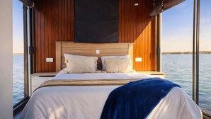 Ein Bett mit Holz Kopfteil, weißer Bettwäsche und einer blauen Tagesdecke.