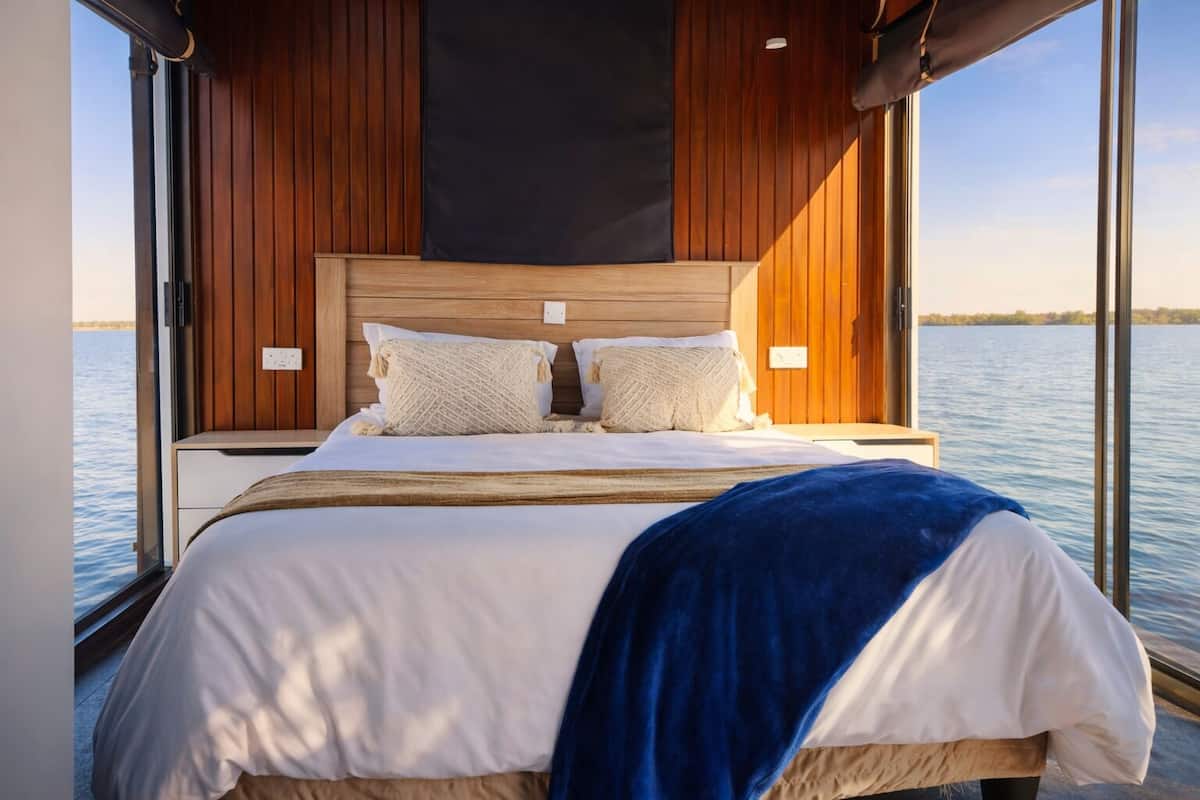 A bed with a wooden headboard, white bedding, and a blue throw blanket.