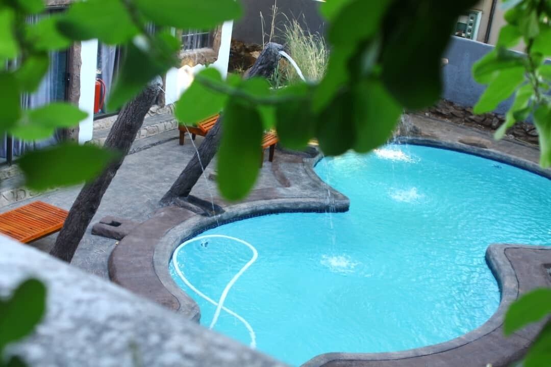 Una piscina con muelle de madera y sillas de descanso.