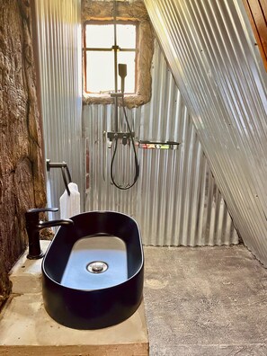 A bathroom with a black sink, a window, and a towel rack.