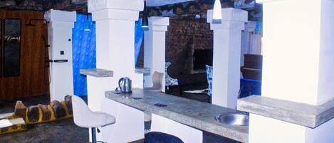 A modern kitchen with white bar stools, a granite countertop, and a stone backsplash.